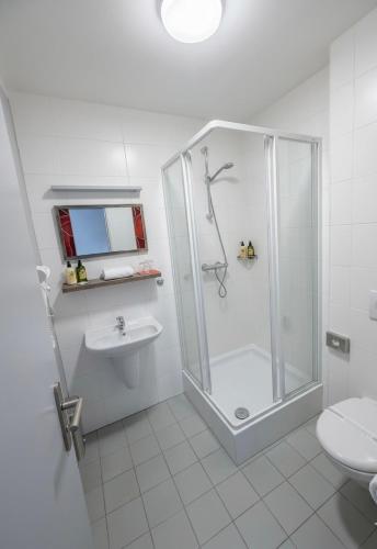 a white bathroom with a shower and a toilet at Hotel Olympia in Kopřivnice