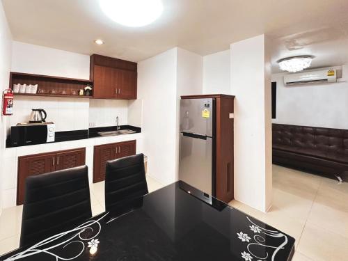 a kitchen with a black table and a refrigerator at บ้านเกื้อ เดอะ ลิฟวิ่ง in Nakhon Ratchasima