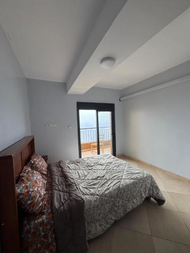 a bedroom with a bed and a large window at Harmony immo in Bir el Djir