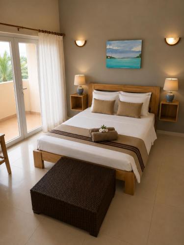 a bedroom with a large bed and a large window at ARIEL BEACH VILLA* in Grand-Baie