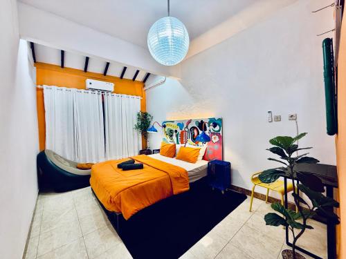 a bedroom with a bed with an orange blanket at HHHH Hostel in Banyuwangi