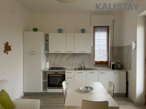 a kitchen with white cabinets and a table and a sink at Casa Francesca Appartamento a 200m dal mare in Torre Canne