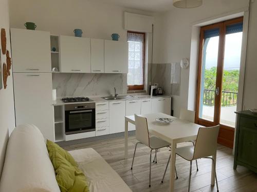 a kitchen with white cabinets and a table and chairs at Casa Francesca Appartamento a 200m dal mare in Torre Canne