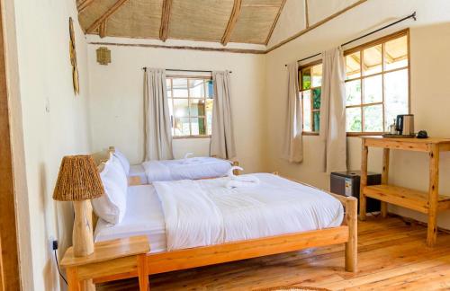 a bedroom with a bed and two windows at Riverside Gorilla Lodge - Bwindi in Kinkizi