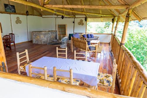 a room with a table and chairs on a porch at Riverside Gorilla Lodge - Bwindi in Kinkizi