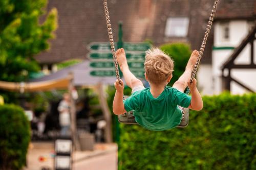 a young boy is swinging on a swing at Familotel Borchards Rookhus in Wesenberg