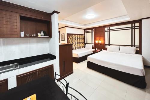 a hotel room with two beds and a kitchen at บ้านเกื้อ เดอะ ลิฟวิ่ง in Nakhon Ratchasima