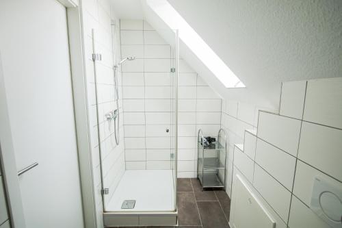 a white bathroom with a shower and a glass door at Murthum Apartments in Leinfelden-Echterdingen