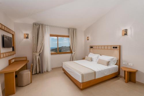 a white bedroom with a bed and a window at Hotel Rocce Sarde in San Pantaleo