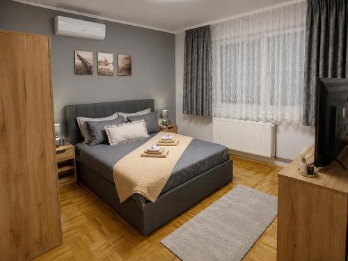 a bedroom with a large bed and a television at Apartman Ivano in Vukovar