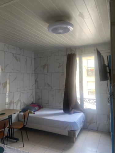 a bedroom with a bed and a table and a window at Hôtel Cyrano Voltaire in Paris