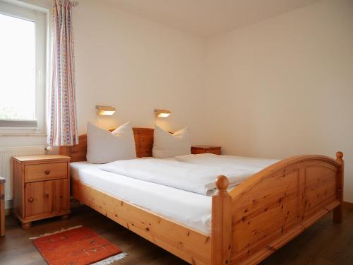 a bedroom with a wooden bed with white sheets at Tschach in Kirchdorf