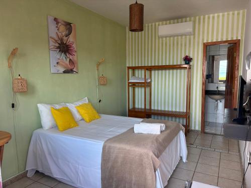 a bedroom with a large white bed with yellow pillows at Pequena Sereia Guriri in São Mateus