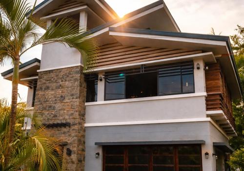 a house with a palm tree in front of it at Island Lyfe Adventures Hotel - 5 Minutes from El Nido Airport & Lio Beach in El Nido