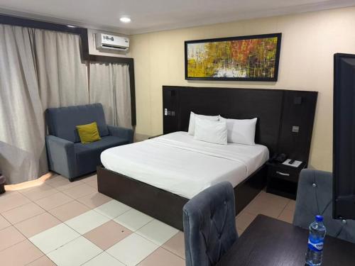 a bedroom with a bed and two chairs and a table at NO 95 Suites LEKKI PHASE 1 in Ilado
