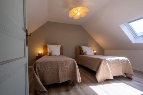 a attic room with two beds and a window at L'ecrin de séraphie in Nojaret