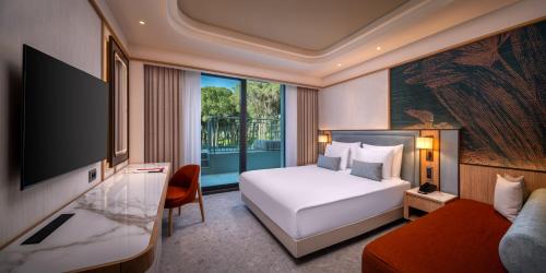 a hotel room with a bed and a television at Trendy Perge Resort & Suites in Aksu