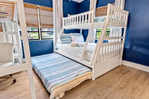a white bunk bed in a room with blue walls at Surf Drive - Ultimate Beach Getaway for Families in Cocoa Beach