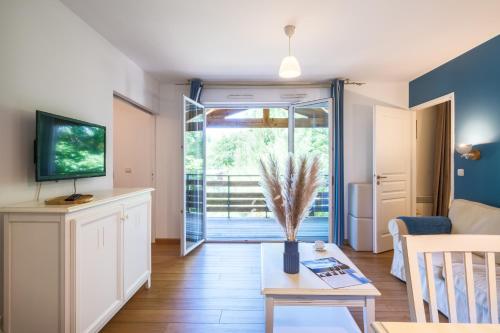 a living room with a couch and a tv and a table at Résidence Pierre & Vacances Les Cottages Du Lac in Parentis-en-Born