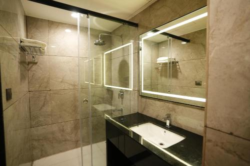 a bathroom with a sink and a shower with a mirror at Hotel Shubham Celebrations-Miyapur in Lingampalli