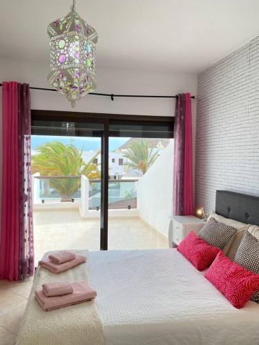 a bedroom with a bed with pink pillows and a chandelier at Casa Candy. Piscina, Mar y Paz. in Tuineje