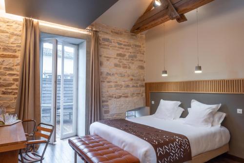 a bedroom with a large bed and a large window at Hotel Aux Terrasses in Tournus