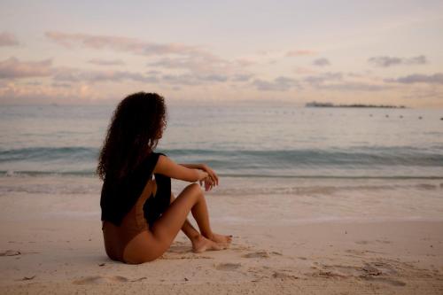 a woman sitting on the beach looking at the ocean at Rosewood Baha Mar in Nassau
