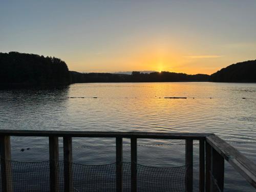 a view of a lake with the sun setting at Chalets flottants lac de Saint Étienne Cantalès in Saint-Gérons