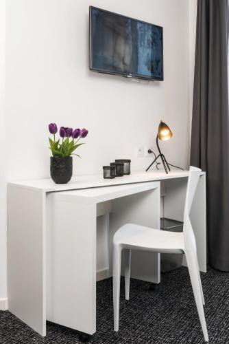 a white desk with a chair and a vase of flowers at Ténéo Apparthotel Talence Espeleta - Bordeaux Sud in Talence