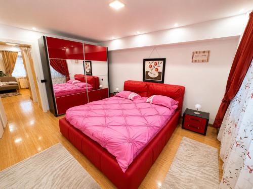 a bedroom with a red bed and a mirror at Bella Casa Apartments in Făgăraş