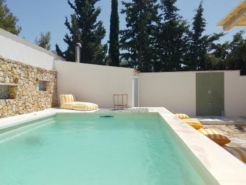 a swimming pool with two chairs and a table at LE SORELLE Sea front -villa whit private pool in Scopello