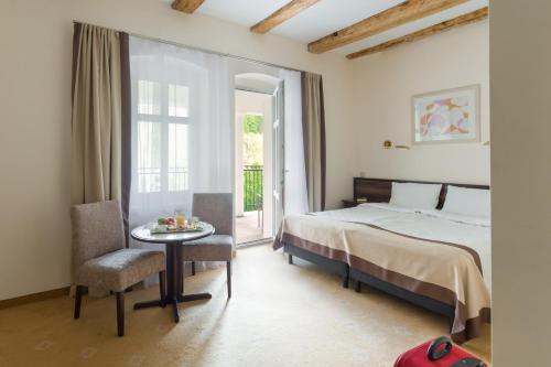1 dormitorio con cama, mesa y ventana en Impresja Art Resort en Duszniki Zdrój