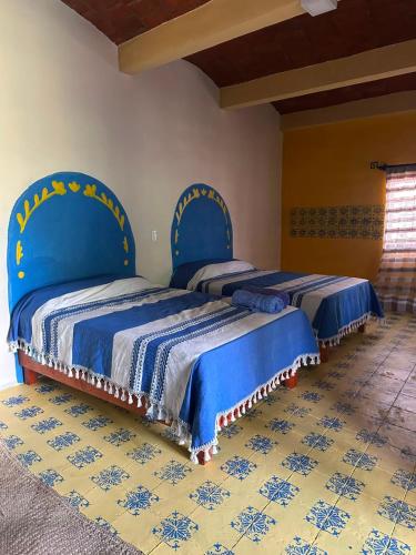 two beds with blue covers in a room at Ojo de Luna Teotitlan in Teotitlán del Valle