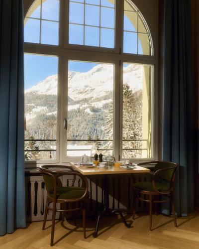 a table and chairs in front of a large window at Grand Hotel Belvedere, a Beaumier Hotel in Wengen