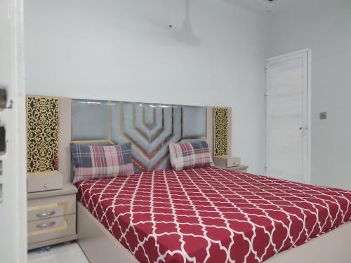 a bedroom with a bed with a red comforter at Lasani view Guest House in Lahore