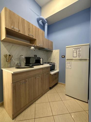 a kitchen with wooden cabinets and a white refrigerator at Queen-V Hostel in Vlorë