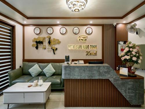 a salon with a couch and clocks on the wall at NEW SUN NAM ĐỊNH hotel in Nam Ðịnh
