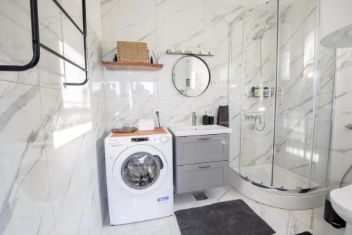 a white bathroom with a washing machine in it at Golubek Holiday House in Banščica
