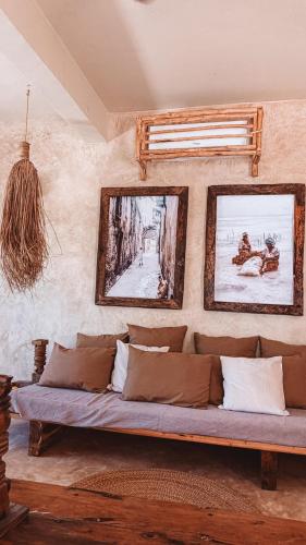 a couch in a room with paintings on the wall at Villa Upendo with Private Pool and Ocean View Zanzibar in Pingwe