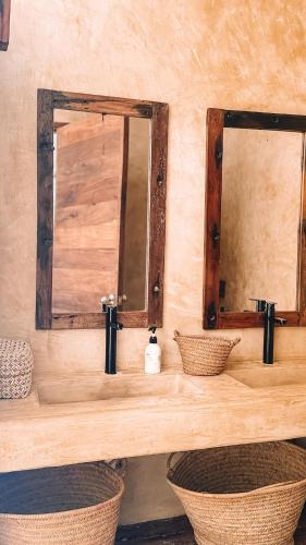a bathroom with two sinks and two mirrors at Villa Upendo with Private Pool and Ocean View Zanzibar in Pingwe