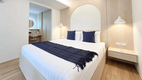 a bedroom with a large white bed with blue pillows at Peaceful Fantasia Condo Kamala in Surin Beach