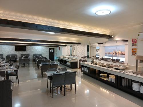 a restaurant with tables and chairs and a buffet at Downtown Business Hotel in Singapperumālkovil