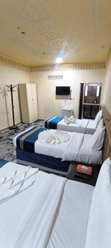 a hotel room with three beds and a flat screen tv at Zad Al Hayat in Mecca