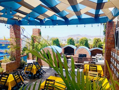 a patio with yellow chairs and a blue umbrella at Hotel Magico del Mar in La Paz