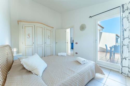 a white bedroom with a bed and a large window at Chic Residence Ea Bianca 1 Bed Apartment sleeps 4 in Cala Bitta