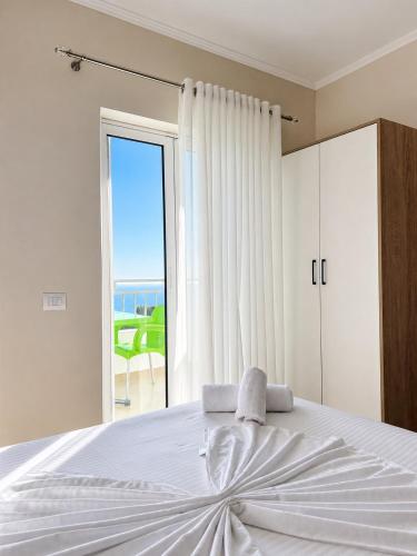 a bedroom with a white bed and a large window at Lukova Center Sunset Apartments in Lukovë