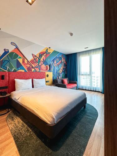 ein Schlafzimmer mit einem Bett und einem Gemälde an der Wand in der Unterkunft Axis Hotel in Cimenli