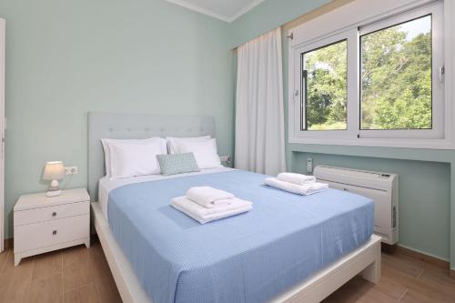 a bedroom with a blue bed with towels on it at Yi Garden Corfu in Corfu