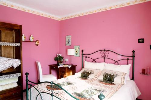 um quarto rosa com uma cama e uma cadeira em Guest House I Vicini di Cesare em Castelnuovo