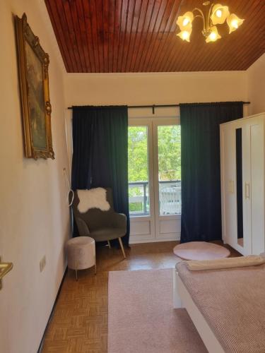 a bedroom with a bed and a chair and a window at Simay Apartman II in Balatonalmádi